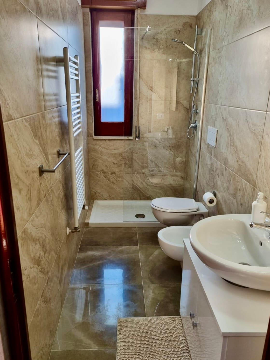 Bagno rivestito in marmo con ampia doccia