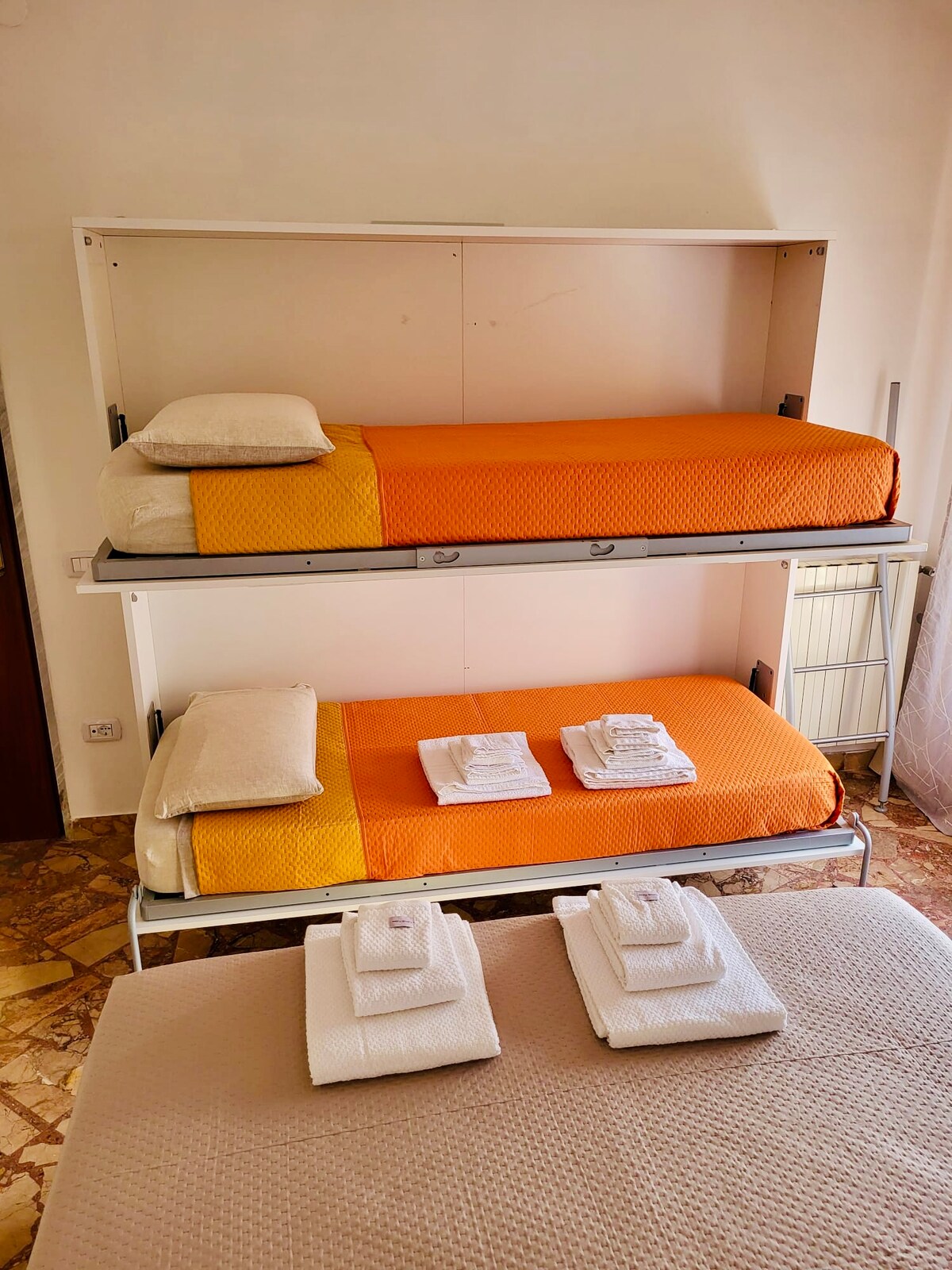 Il letto a castello aperto, con due letti singoli e biancheria arancione